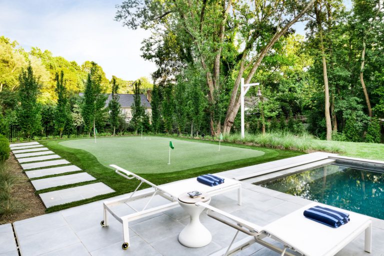 A curved drive, hornbeam hedge, allée of birches, and wildflower meadow together create privacy and lovely elements of surprise on the approach to this new house, which was designed for entertaining. Luxurious, but low-maintenance native and adaptive plantings are integrated into the overall landscape plan to balance the considerable hardscaping and define the lawns. At the front of the house, a massive parking court with subtly striped paving and an elegant retaining wall create a distinctive outdoor room. Guests have a variety of gathering spaces at the rear of the house that include upper and lower terraces for seating and dining, a putting green, and pool and pool deck. A large rain garden in the lower slope completes the program requirements by absorbing drainage and recharging the aquifer.