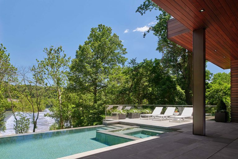 The masterplan for this unique property — a steeply sloping three-acre site and riverfront clearing — included stabilizing eroded creeks, restoring wetlands, and incorporating a massive rain garden to filter storm water flow from the parking court above and other properties further up the hill. The owners, a family with four dogs, also had requirements that included adequate parking for entertaining, a dedicated recreation space for the dogs, and a beautifully blended network of new plantings, hardscape, and sculpture to be seen from and complement the linear forms of their organic-modern home in the woods.