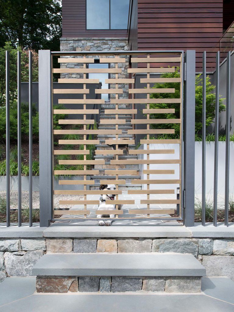 The masterplan for this unique property — a steeply sloping three-acre site and riverfront clearing — included stabilizing eroded creeks, restoring wetlands, and incorporating a massive rain garden to filter storm water flow from the parking court above and other properties further up the hill. The owners, a family with four dogs, also had requirements that included adequate parking for entertaining, a dedicated recreation space for the dogs, and a beautifully blended network of new plantings, hardscape, and sculpture to be seen from and complement the linear forms of their organic-modern home in the woods.