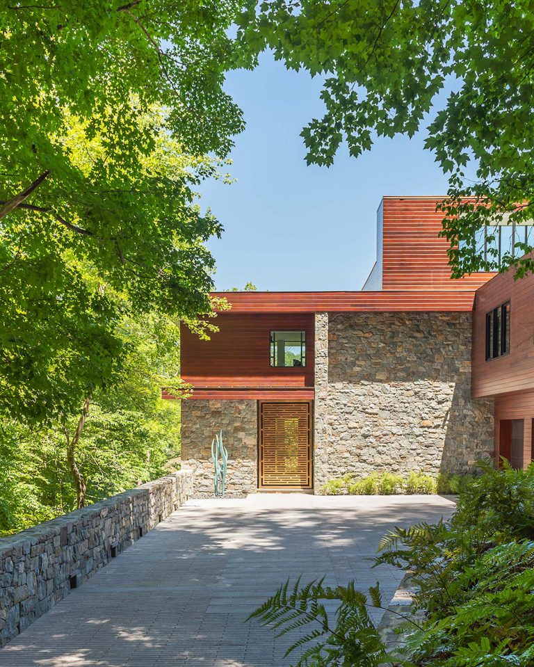 The masterplan for this unique property — a steeply sloping three-acre site and riverfront clearing — included stabilizing eroded creeks, restoring wetlands, and incorporating a massive rain garden to filter storm water flow from the parking court above and other properties further up the hill. The owners, a family with four dogs, also had requirements that included adequate parking for entertaining, a dedicated recreation space for the dogs, and a beautifully blended network of new plantings, hardscape, and sculpture to be seen from and complement the linear forms of their organic-modern home in the woods.
