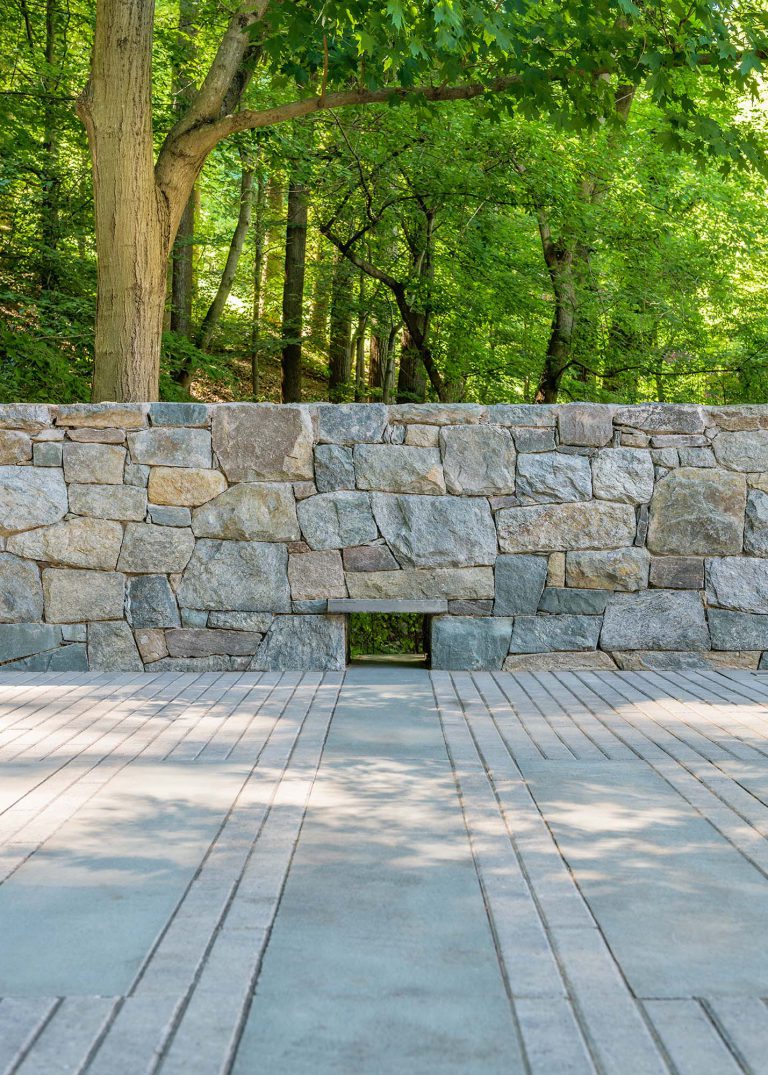 The masterplan for this unique property — a steeply sloping three-acre site and riverfront clearing — included stabilizing eroded creeks, restoring wetlands, and incorporating a massive rain garden to filter storm water flow from the parking court above and other properties further up the hill. The owners, a family with four dogs, also had requirements that included adequate parking for entertaining, a dedicated recreation space for the dogs, and a beautifully blended network of new plantings, hardscape, and sculpture to be seen from and complement the linear forms of their organic-modern home in the woods.
