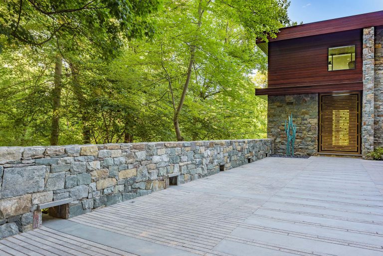 The masterplan for this unique property — a steeply sloping three-acre site and riverfront clearing — included stabilizing eroded creeks, restoring wetlands, and incorporating a massive rain garden to filter storm water flow from the parking court above and other properties further up the hill. The owners, a family with four dogs, also had requirements that included adequate parking for entertaining, a dedicated recreation space for the dogs, and a beautifully blended network of new plantings, hardscape, and sculpture to be seen from and complement the linear forms of their organic-modern home in the woods.