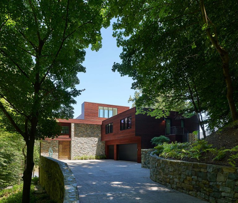 The masterplan for this unique property — a steeply sloping three-acre site and riverfront clearing — included stabilizing eroded creeks, restoring wetlands, and incorporating a massive rain garden to filter storm water flow from the parking court above and other properties further up the hill. The owners, a family with four dogs, also had requirements that included adequate parking for entertaining, a dedicated recreation space for the dogs, and a beautifully blended network of new plantings, hardscape, and sculpture to be seen from and complement the linear forms of their organic-modern home in the woods.