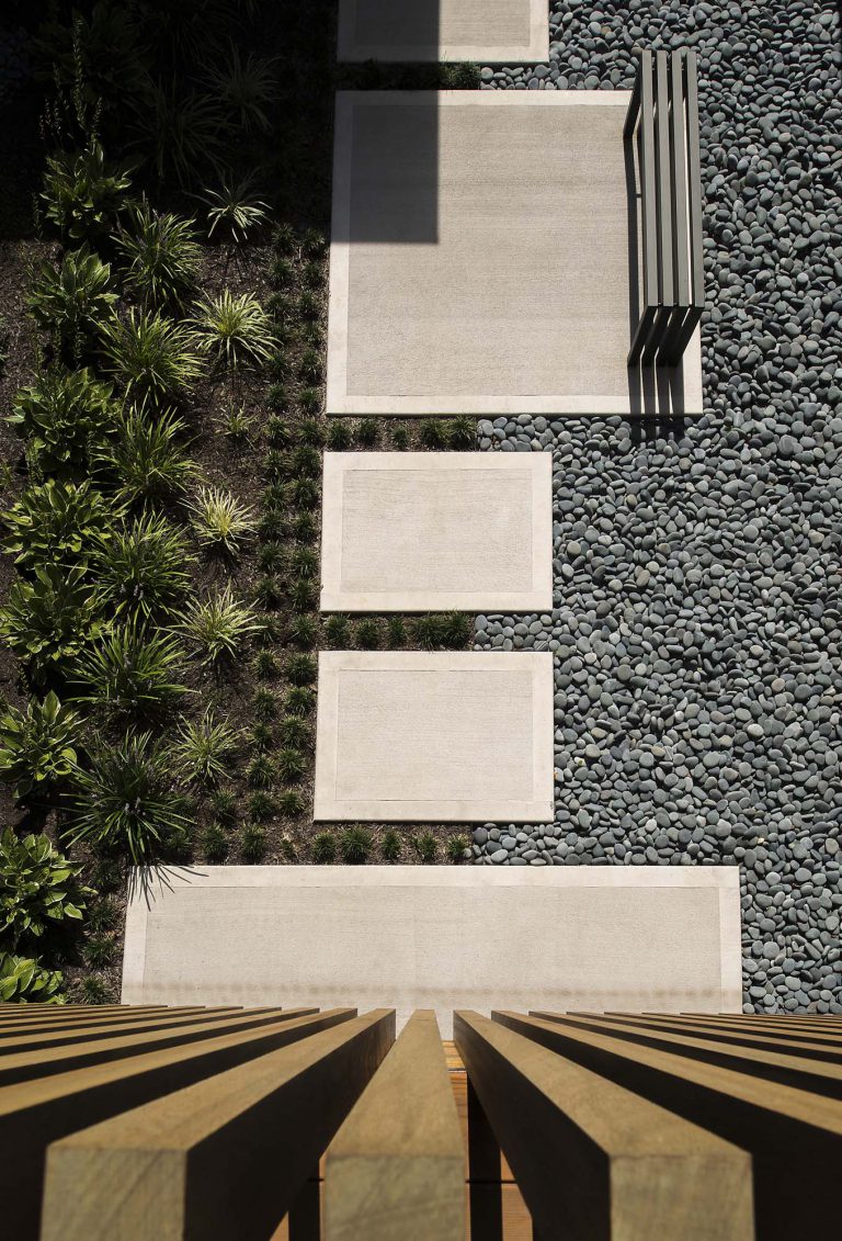 The landscape objectives for this unusual c. 1965 house included a welcoming entrance courtyard, privacy for the rear yard garden and pool area, and consideration for the drainage issues inherent to the property. The design, which evolved comprehensively along with the renovation of the house, evokes that of a Japanese garden. The inner court is a calm, peaceful space that belies the complexity of the project. The staggered concrete stepping pads, river stones, and low plantings can be seen from numerous rooms within the house, blurring the lines of where the garden begins and ends. At the rear, hand-cut stone was used for the terraces and pool coping while the pool deck is architectural concrete. A screen of Black Cane Bamboo (Phyllostachys nigra) and River Birch (Betula nigra) contribute to the contemplative planting scheme.